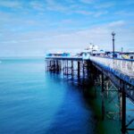Pier in North Wales with blue sea blue sky and a small sail boat