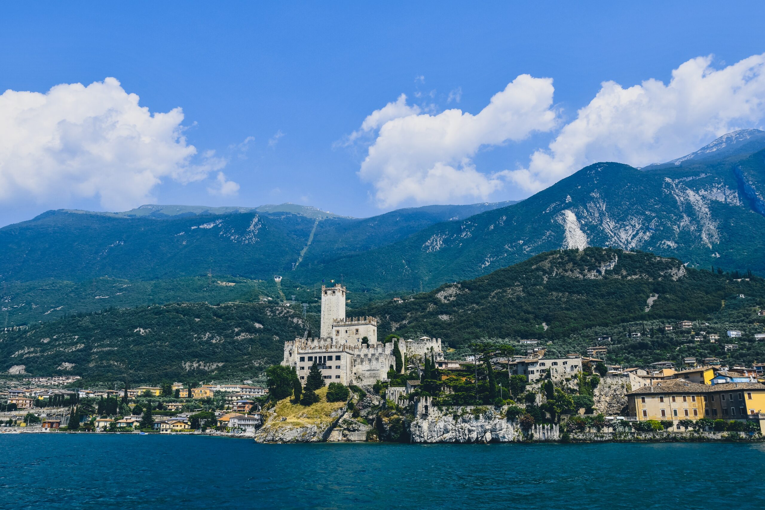 Town and castle of Malcesine against mountains blue sky and a lake
