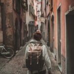 Woman with backpack walks through alley