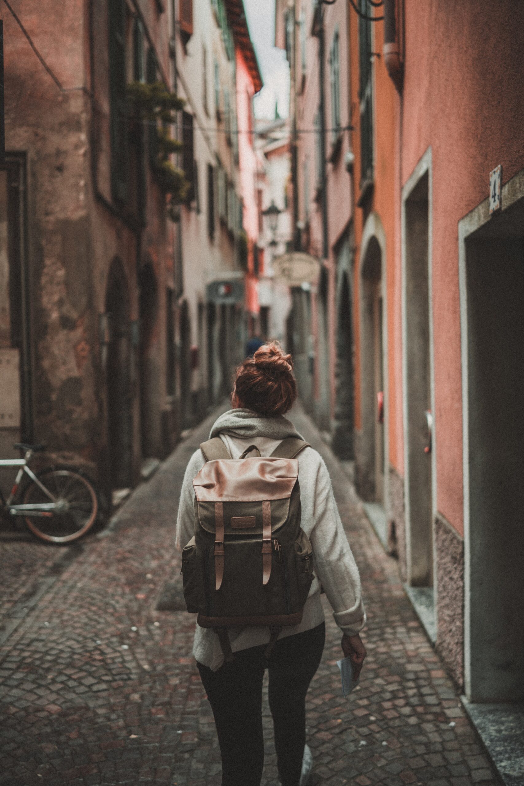 Woman with backpack walks through alley