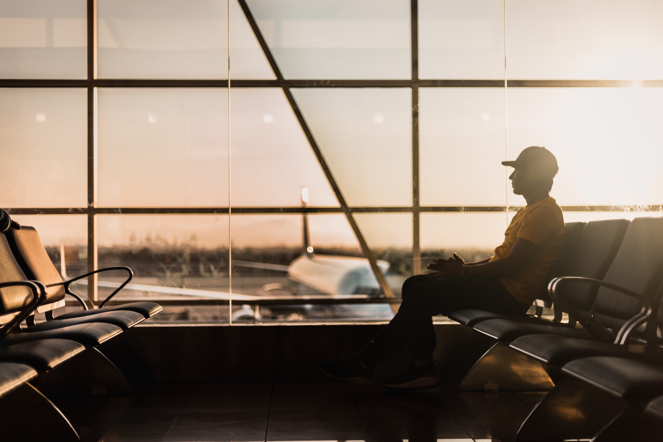 A man sits in an airport as the sun goes down