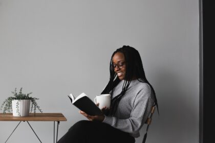 Reading list for Mother's Day - Roonee. A woman reading a book with a cup of tea in her hand