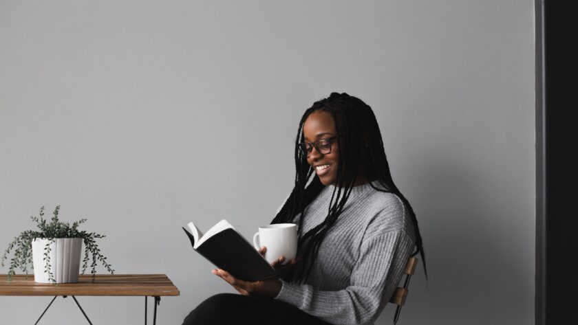 Reading list for Mother's Day - Roonee. A woman reading a book with a cup of tea in her hand