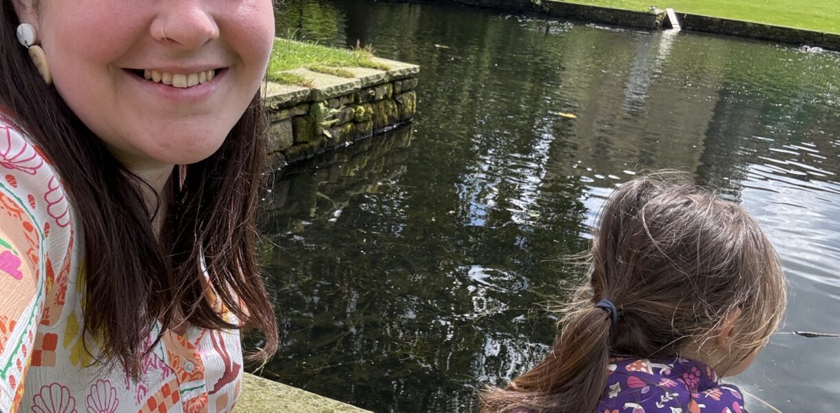 Alex with her daughter outside by a big pond