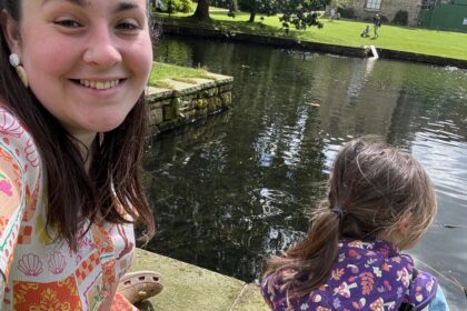 Alex with her daughter outside by a big pond