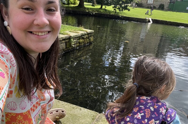 Alex with her daughter outside by a big pond