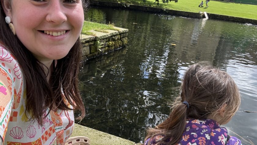 Alex with her daughter outside by a big pond