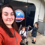 Alex stands in front of a National Space Centre sign with her two young twins