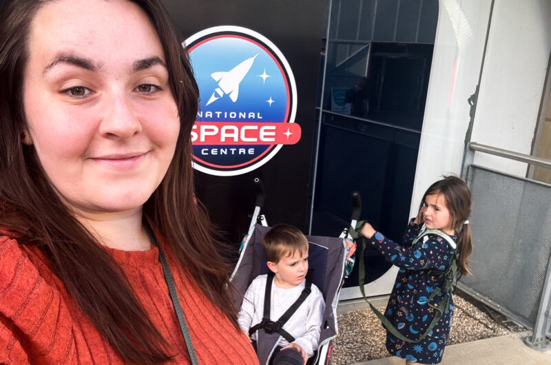 Alex stands in front of a National Space Centre sign with her two young twins