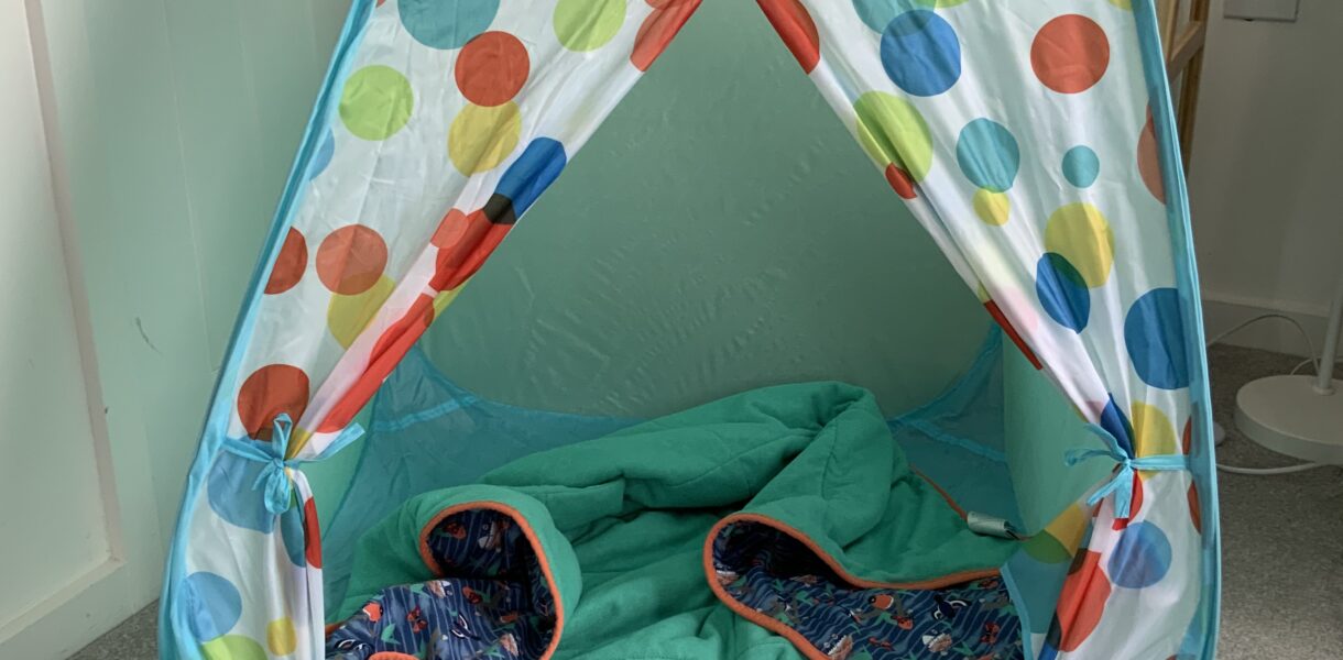 a pop up play tent with a spotty design and a blanket inside