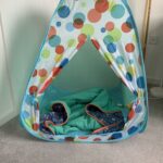 a pop up play tent with a spotty design and a blanket inside