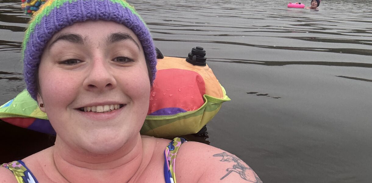 Alex swimming outdoors wearing a colourful bobble hat