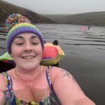 Alex swimming outdoors wearing a colourful bobble hat