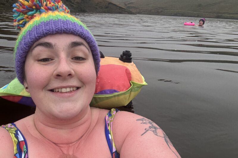 Alex swimming outdoors wearing a colourful bobble hat