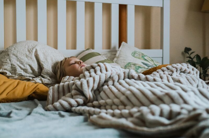 a child sleeps under a soft looking blanket