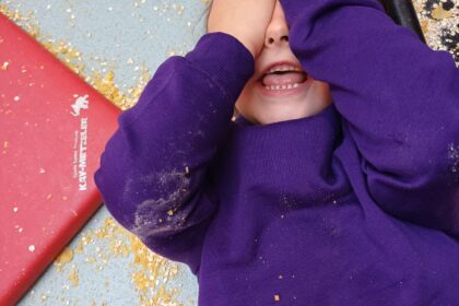 a happy child in a purple jumper